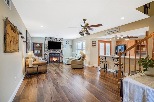 living area featuring ceiling fan, a fireplace, wood finished floors, and baseboards