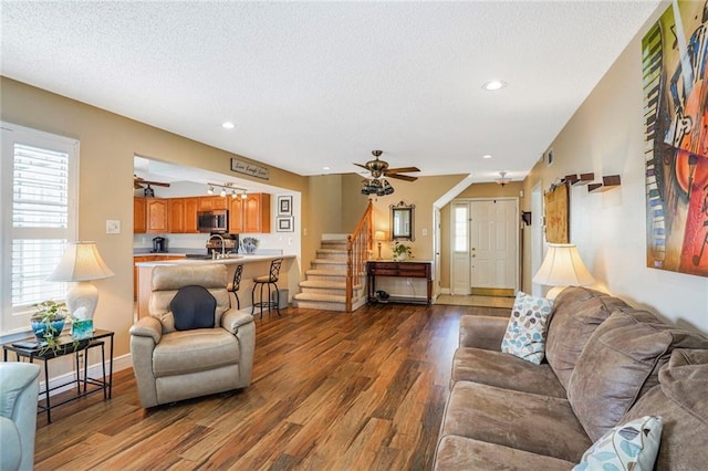 living room featuring stairs, a textured ceiling, dark wood finished floors, and recessed lighting