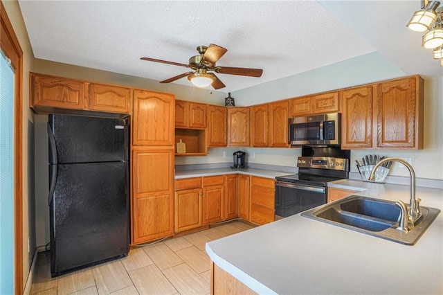 kitchen featuring stainless steel appliances, brown cabinetry, a sink, and a ceiling fan