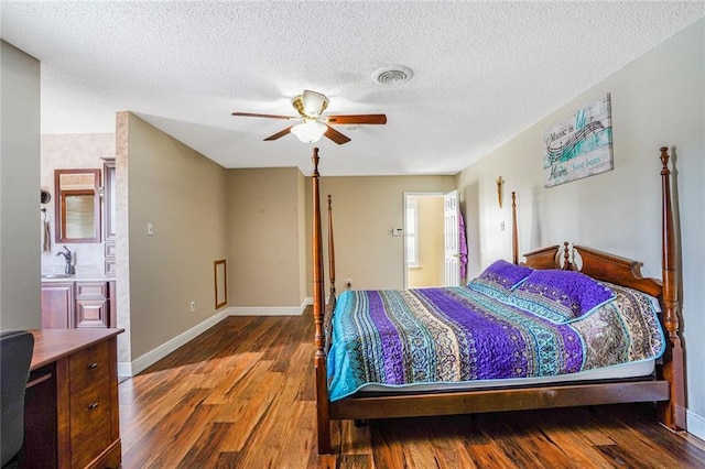 bedroom featuring ceiling fan, a sink, wood finished floors, visible vents, and baseboards