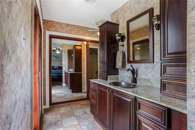 ensuite bathroom with ensuite bath, ceiling fan, a textured ceiling, and vanity