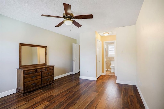 bedroom featuring baseboards, dark wood finished floors, ceiling fan, ensuite bath, and a textured ceiling