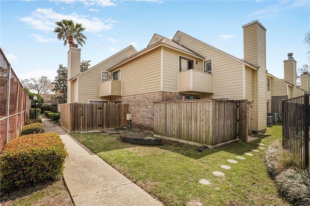 view of home's exterior with brick siding, fence, a lawn, and central AC unit