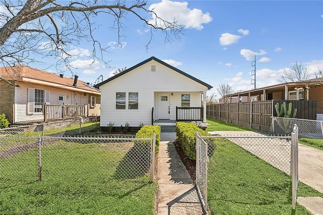 view of front facade with covered porch, a front lawn, and a fenced front yard