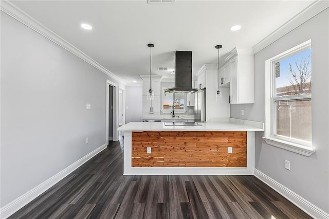 kitchen with a peninsula, baseboards, island range hood, and light countertops