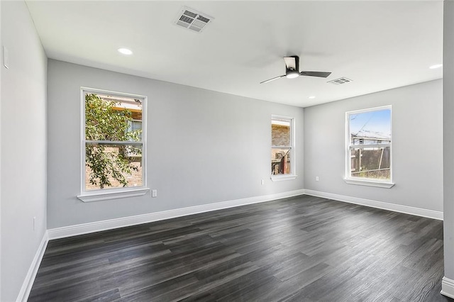 empty room featuring visible vents, dark wood finished floors, and baseboards