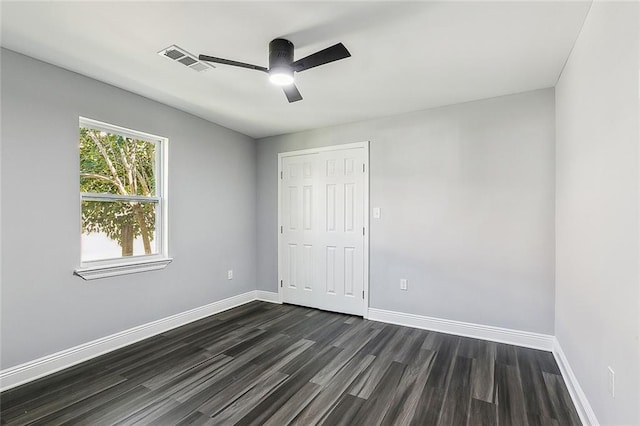 unfurnished bedroom featuring dark wood-style floors, visible vents, baseboards, and a ceiling fan