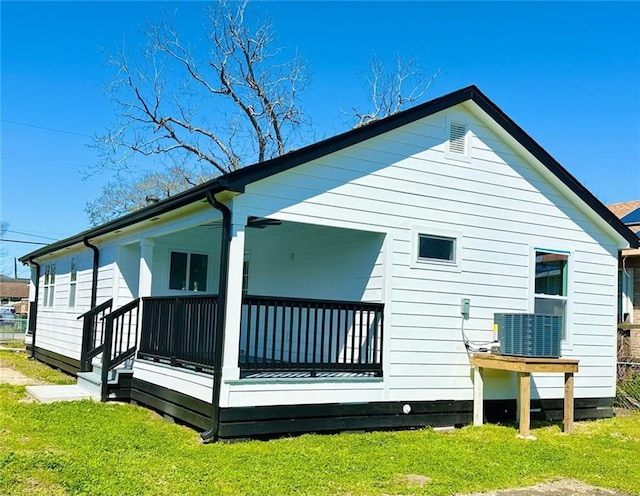 back of house featuring a porch, cooling unit, and a yard