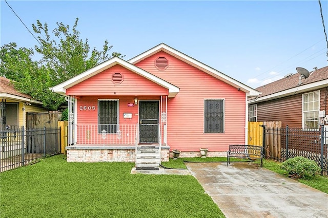 view of front of property featuring covered porch, fence, and a front lawn