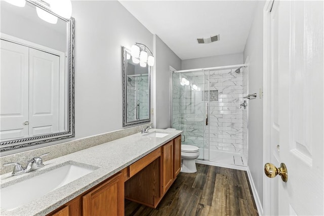 full bathroom featuring toilet, a sink, visible vents, and a shower stall