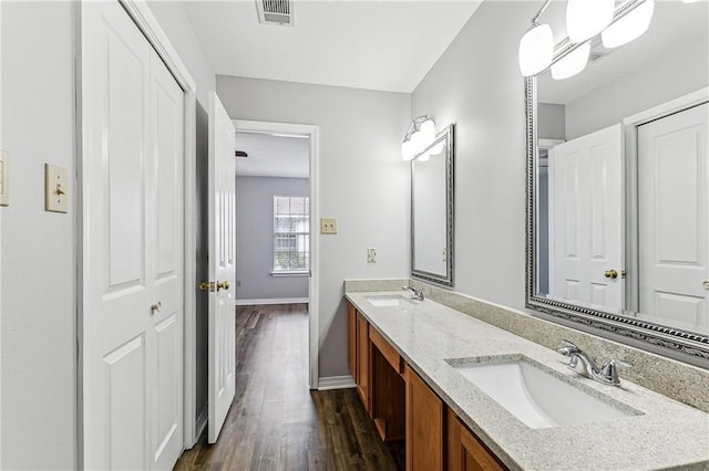 bathroom with double vanity, visible vents, a sink, and wood finished floors