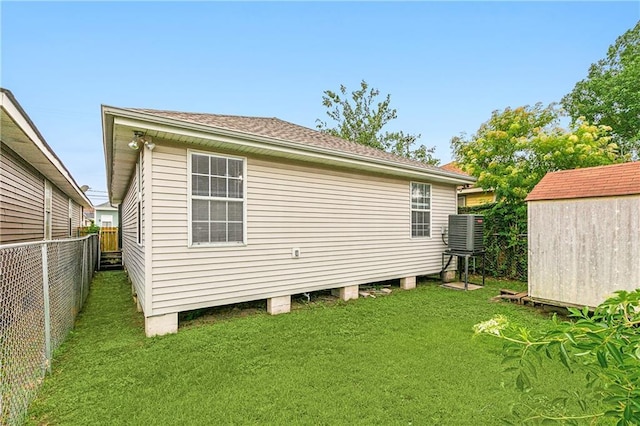 view of home's exterior with a yard, a storage shed, central AC, a fenced backyard, and an outdoor structure