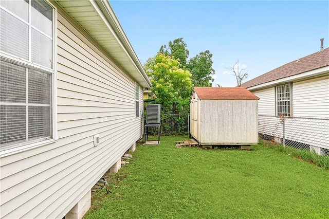 view of yard featuring a storage shed, fence, and an outbuilding