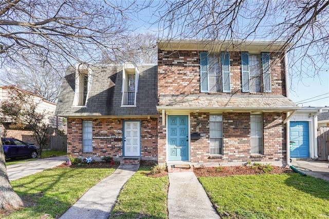 view of front of house featuring a front lawn, fence, and brick siding