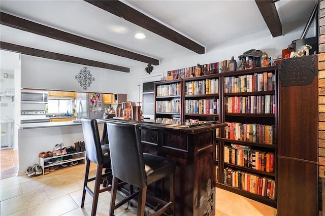 dining space featuring light tile patterned floors, a bar, beam ceiling, and recessed lighting