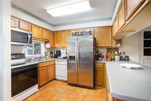 kitchen with stainless steel appliances, a peninsula, light countertops, and brown cabinets