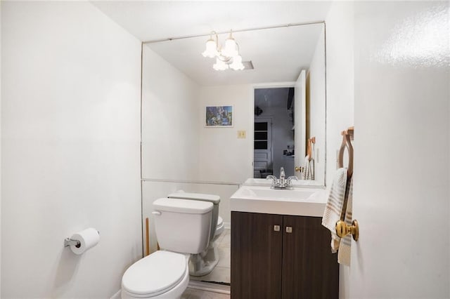 bathroom featuring a notable chandelier, vanity, and toilet