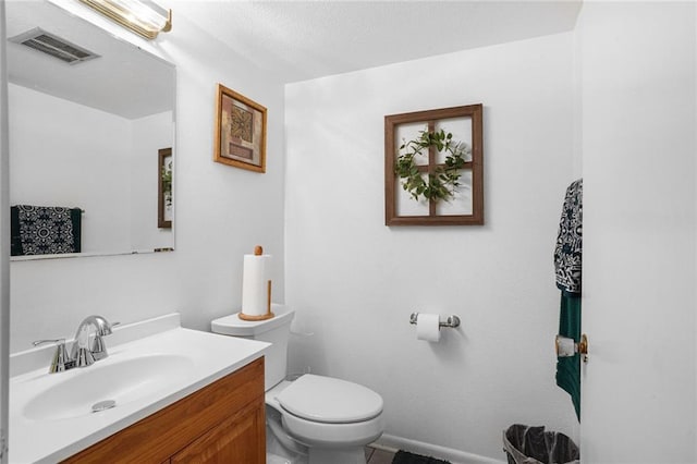 bathroom featuring toilet, vanity, and visible vents