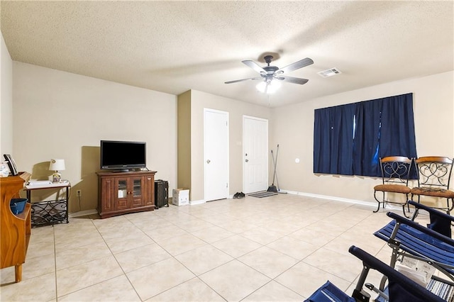 interior space with light tile patterned floors, visible vents, a ceiling fan, a textured ceiling, and baseboards