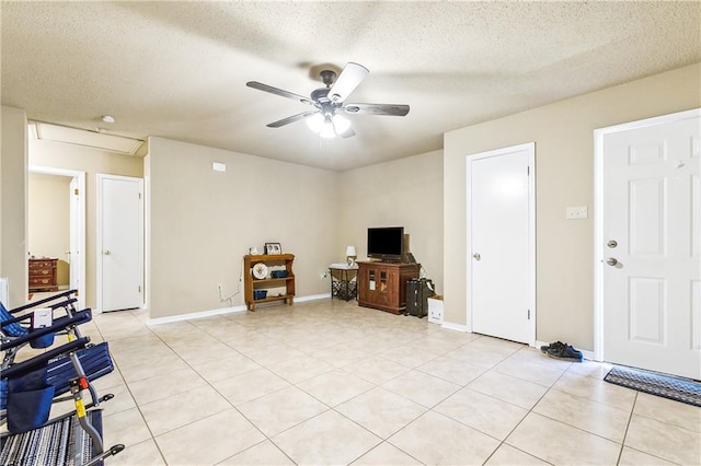 interior space featuring light tile patterned floors, ceiling fan, a textured ceiling, and baseboards