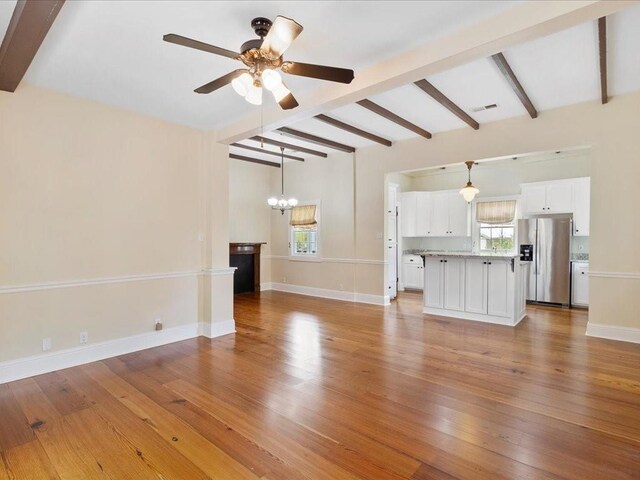 unfurnished living room featuring light wood-type flooring, beam ceiling, visible vents, and baseboards