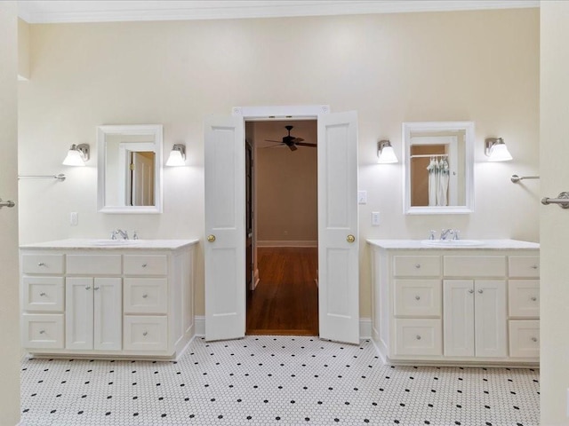 bathroom with crown molding, two vanities, and a sink