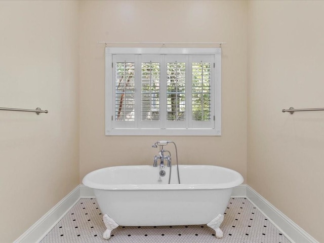 full bath featuring a freestanding bath, tile patterned flooring, and baseboards