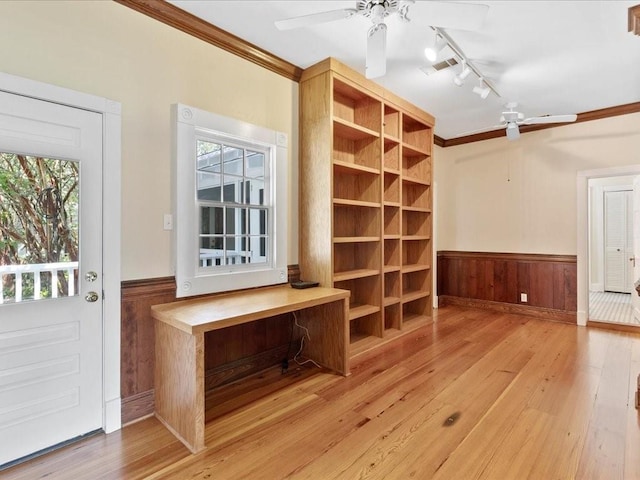 interior space featuring a ceiling fan, a wainscoted wall, hardwood / wood-style flooring, rail lighting, and crown molding