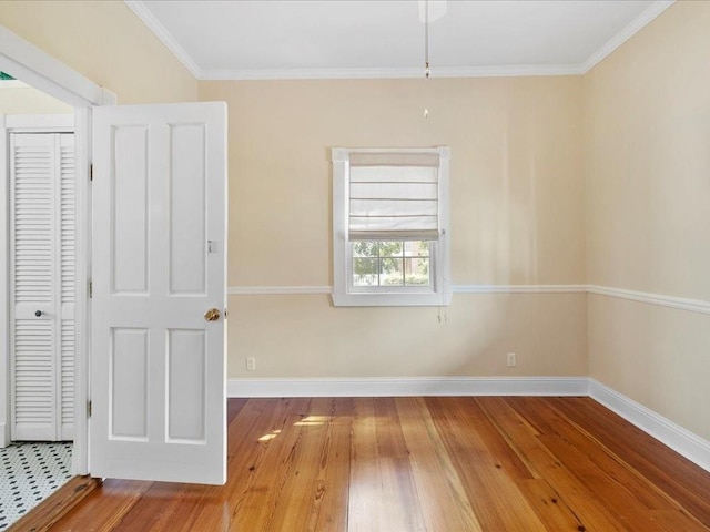 unfurnished room featuring crown molding, wood finished floors, and baseboards