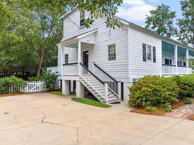 view of front of home featuring driveway, stairway, and fence