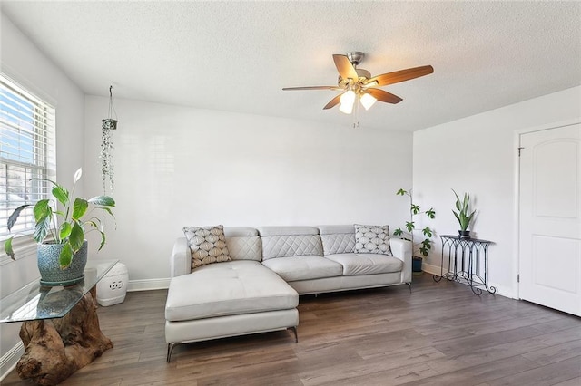 living room featuring baseboards, a textured ceiling, a ceiling fan, and wood finished floors