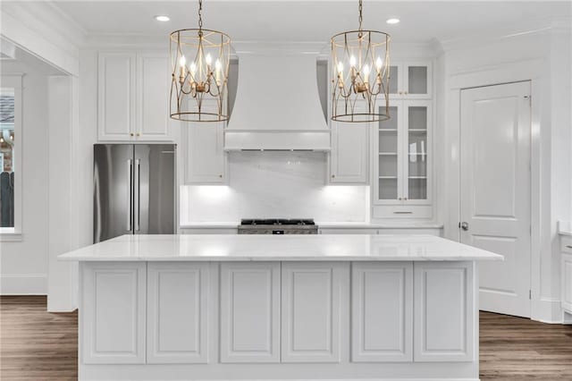 kitchen featuring a notable chandelier, high quality fridge, range, and custom range hood