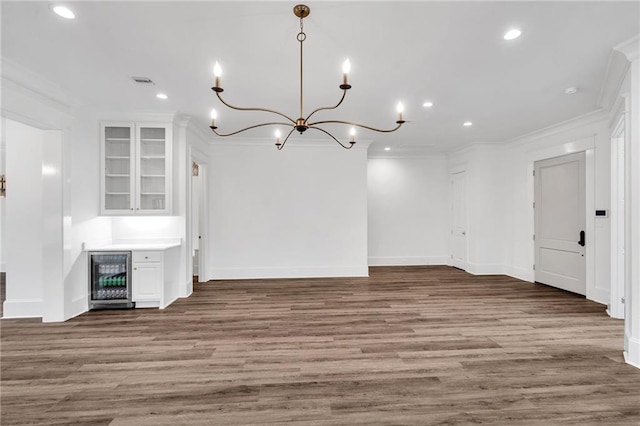 unfurnished living room featuring wine cooler, recessed lighting, wood finished floors, and crown molding