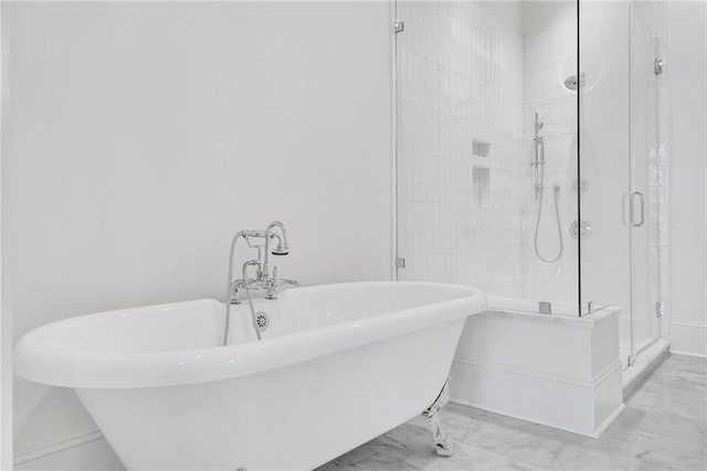 full bath featuring marble finish floor, baseboards, a freestanding bath, and a stall shower