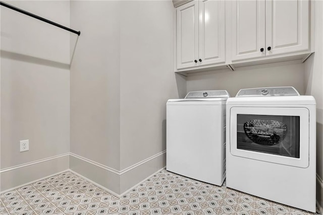 clothes washing area featuring washing machine and dryer, cabinet space, and baseboards