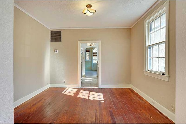 unfurnished room featuring visible vents, plenty of natural light, hardwood / wood-style flooring, and baseboards