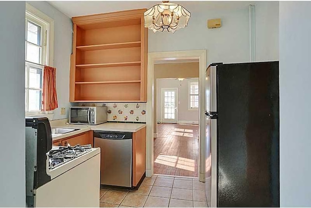 kitchen featuring a notable chandelier, light tile patterned floors, open shelves, light countertops, and appliances with stainless steel finishes