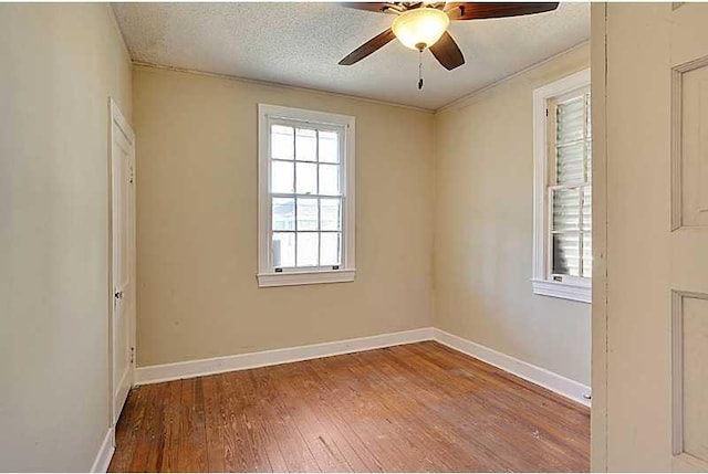 spare room with wood-type flooring, ceiling fan, a textured ceiling, and baseboards