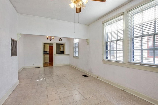 unfurnished room featuring ceiling fan with notable chandelier, visible vents, and a healthy amount of sunlight