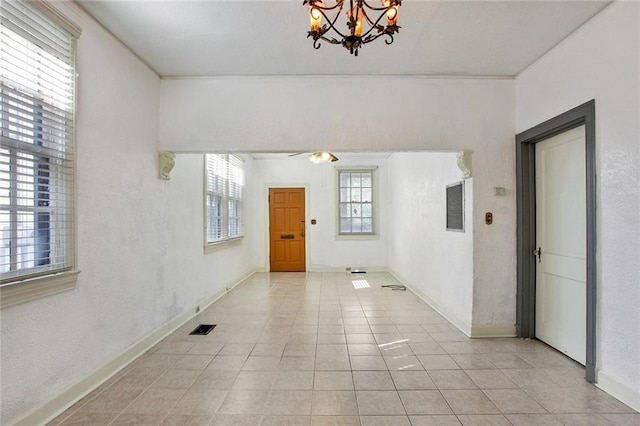 spare room featuring an inviting chandelier, visible vents, a wealth of natural light, and light tile patterned flooring