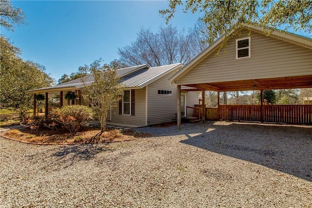 back of property featuring gravel driveway, metal roof, and a carport