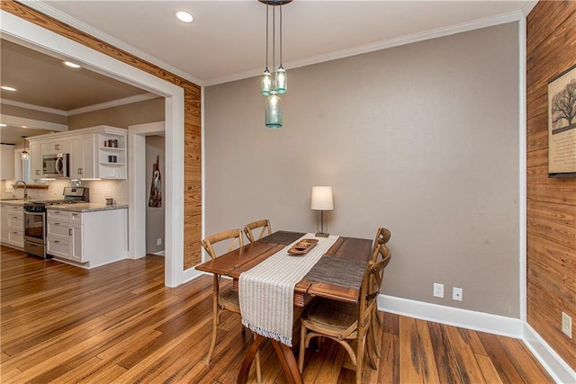 dining space with crown molding, baseboards, wood finished floors, and recessed lighting