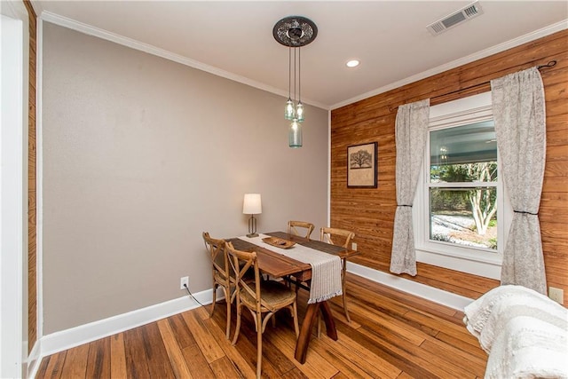 dining area featuring baseboards, wood finished floors, visible vents, and crown molding