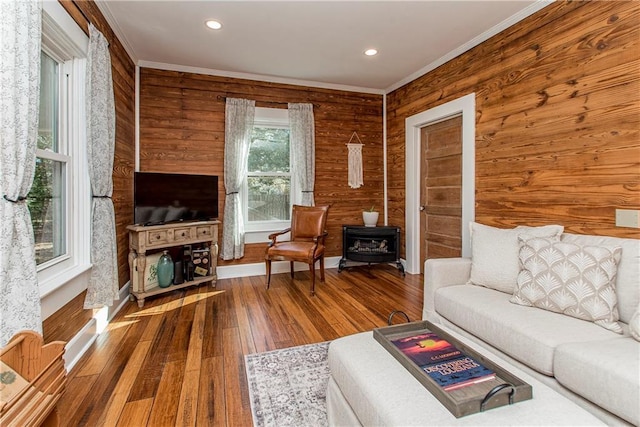 unfurnished living room featuring a wood stove, hardwood / wood-style flooring, ornamental molding, and recessed lighting