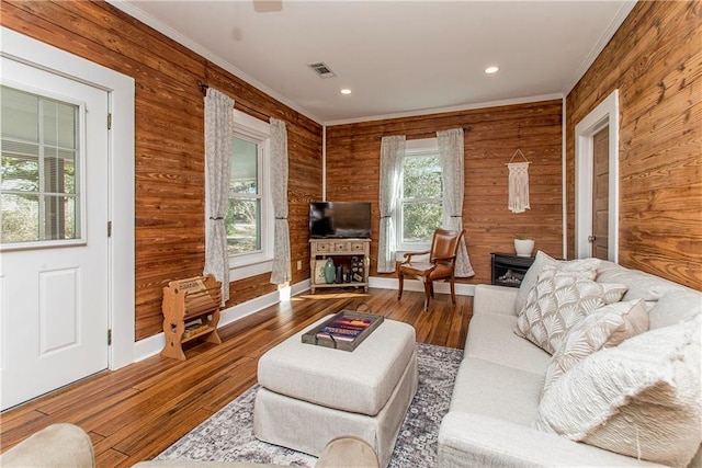 living room with wood-type flooring, visible vents, and crown molding