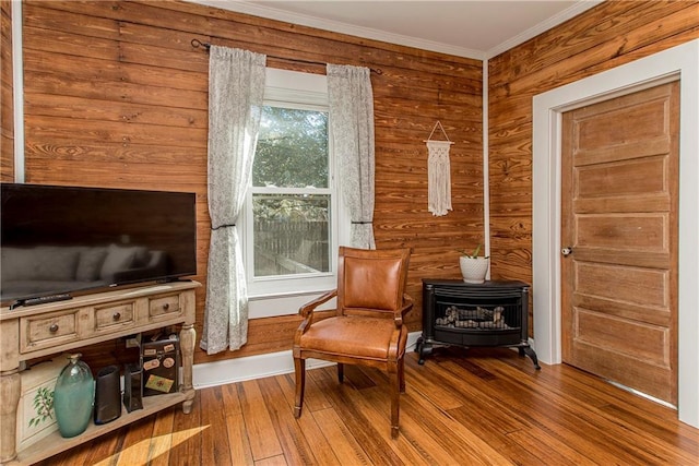 living area featuring a wood stove, hardwood / wood-style flooring, and ornamental molding