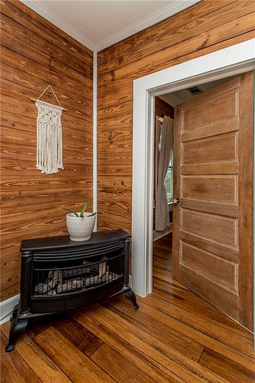 interior details with crown molding, wooden walls, and wood finished floors