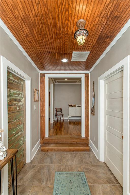 corridor featuring wooden ceiling, visible vents, and crown molding