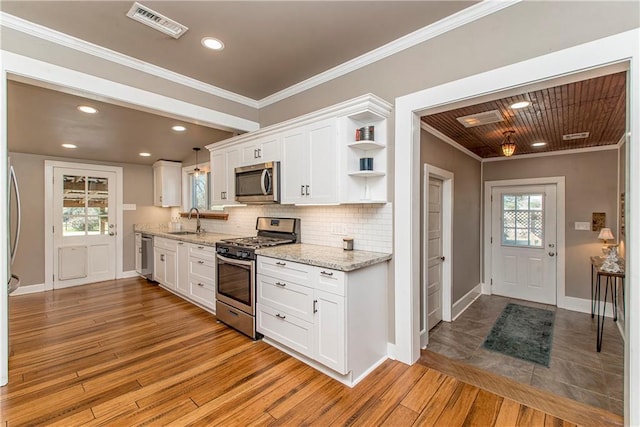 kitchen featuring open shelves, visible vents, appliances with stainless steel finishes, ornamental molding, and a sink