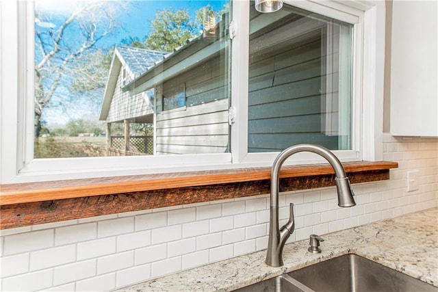 exterior details with white cabinetry, light stone counters, and a sink